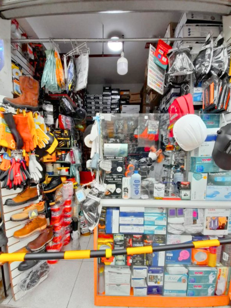 Interior de la tienda Negociaciones Millones mostrando equipos de protección personal: cascos de seguridad blancos, guantes coloridos, calzado de seguridad, respiradores en vitrinas y diversos productos organizados profesionalmente